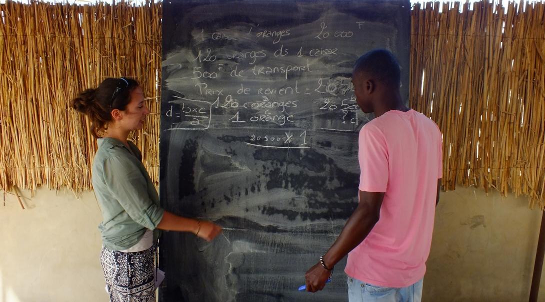A Projects Abroad volunteer speaks to a local at her placement in Senegal. A Teaching volunteer in Senegal helps a local boy during a lesson.